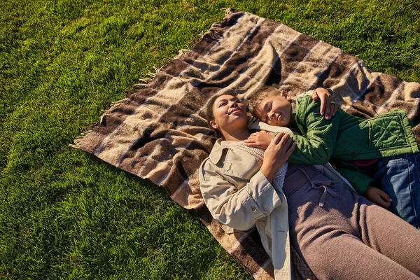 Top view, happiness, motherly love, african american woman and son lying on blanket, autumn fashion — Stock Photo