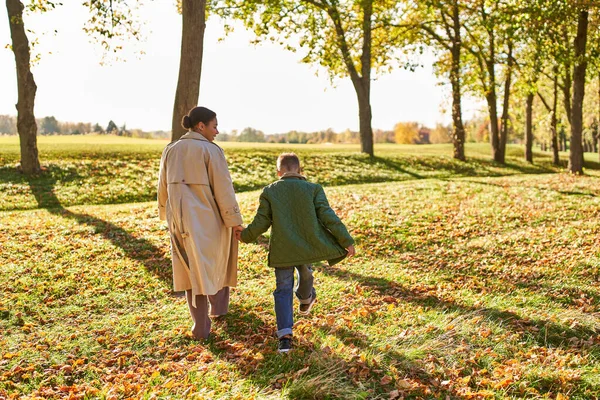 Joyful memories, mother and son walking in park, autumn leaves, fall season, african american family — Stock Photo