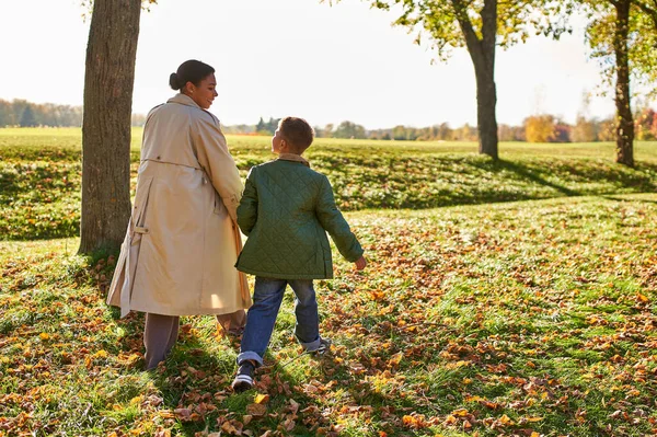 Golden hour, mother and son walking in park, autumn leaves, fall season, african american family — Stock Photo