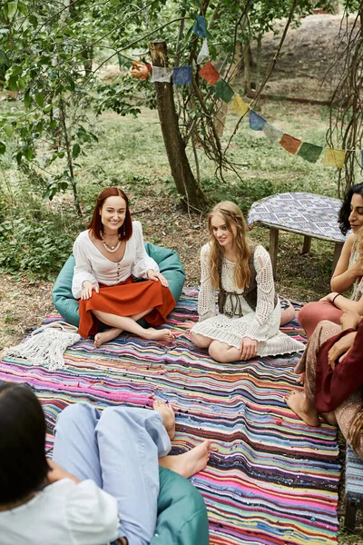 Радісні багатоетнічні жінки в стильному вбранні проводять час на газоні на відкритому повітрі в центрі відпочинку — стокове фото