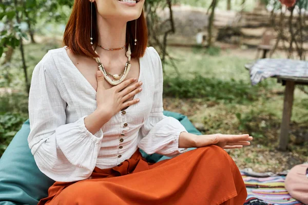 Cropped view of stylish and trendy woman sitting on meadow in retreat center — Stock Photo