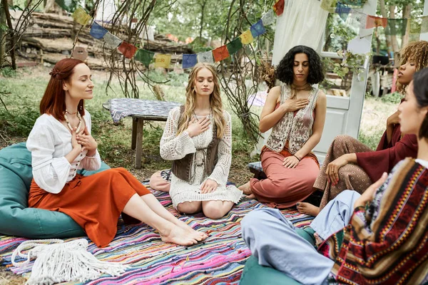 Multiethnic and stylish women in boho styled clothes meditating together in retreat center — Stock Photo