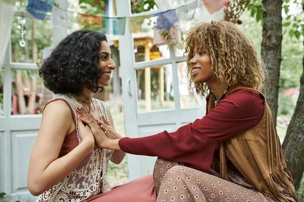 Smiling interracial women in boho outfits meditating together outdoors in retreat center — Stock Photo