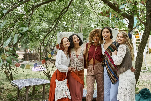 Mujeres positivas y multiétnicas en traje boho mirando a la cámara en el centro de retiro - foto de stock