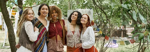 Smiling interracial girlfriends looking at camera outdoors in retreat center, banner — Stock Photo