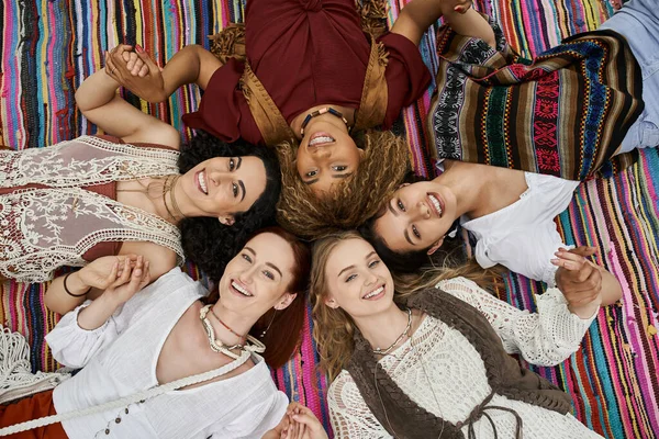 Top view of cheerful interracial women looking at camera on blanket in retreat center — Stock Photo