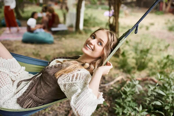Glückliche junge blonde Frau in Boho-Klamotten entspannt sich in der Hängematte im Freien im Rückzugszentrum — Stockfoto