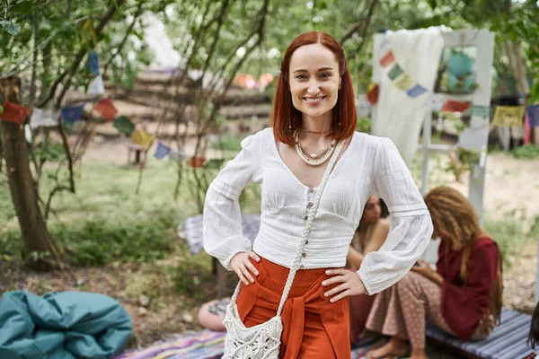Smiling red haired woman in summer outfit looking at camera outdoors in retreat center — Stock Photo