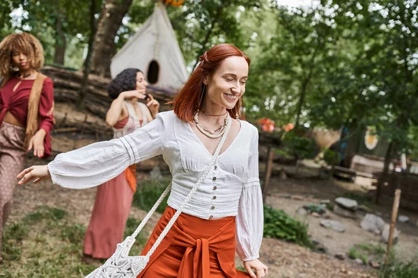 Mulher ruiva alegre em roupa boho passar tempo perto de mulheres multiétnicas no centro de retiro — Fotografia de Stock