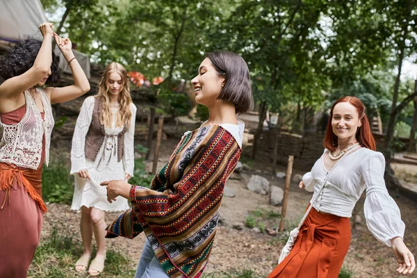 Positive brunette woman in stylish outfit dancing near multiethnic friends in retreat center — Stock Photo
