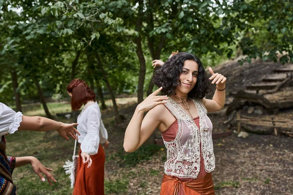 Sorrindo mulher multirracial em roupas da moda olhando para a câmera no prado no centro de retiro — Fotografia de Stock