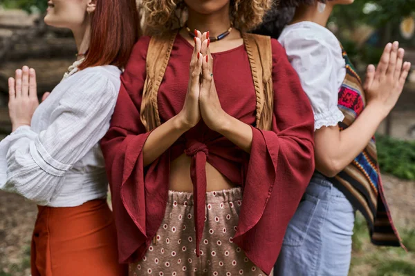 Cropped view of interracial women in stylish clothes doing praying hands gesture in retreat center — Stock Photo