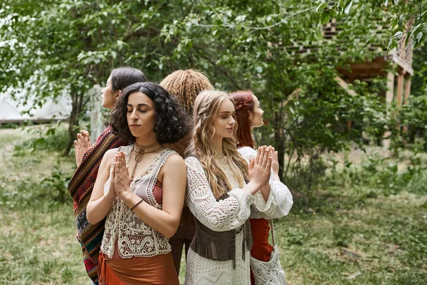 Multiethnic women praying while standing back to back outdoors in retreat center — Stock Photo
