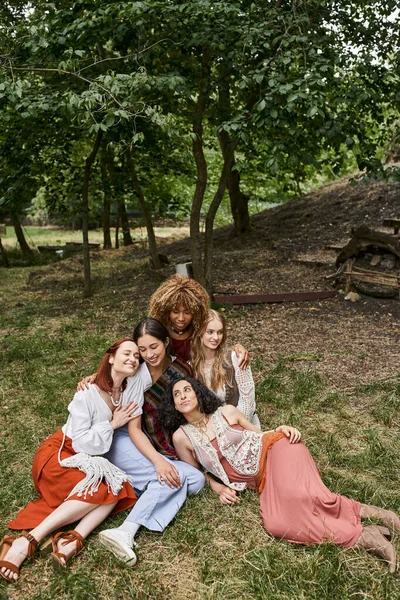 Веселые межрасовые женщины обнимаются, сидя на лугу вместе в центре отдыха — стоковое фото