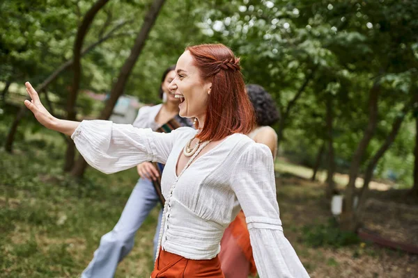 Cheerful redhead woman in stylish outfit having fun with girlfriends in retreat center — Stock Photo