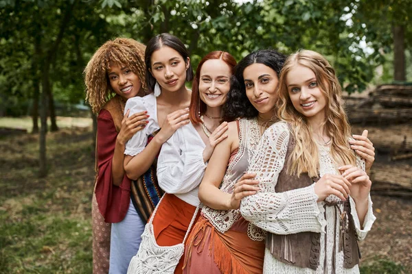 Portrait of cheerful and stylish women in boho styled clothes looking at camera in retreat center — Stock Photo