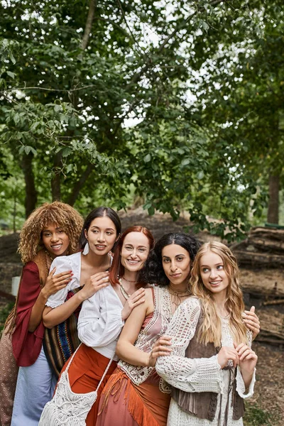 Joyful multiethnic group of women looking at camera and hugging in retreat center — Stock Photo