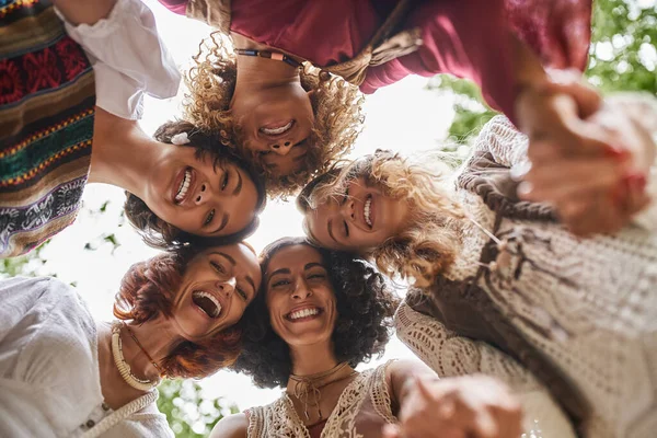 Bottom view of excited multiethnic women looking at camera outdoors in retreat center — Stock Photo