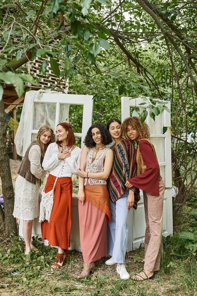 Full length of cheerful and multiethnic women in boho outfits standing in modern retreat center — Stock Photo