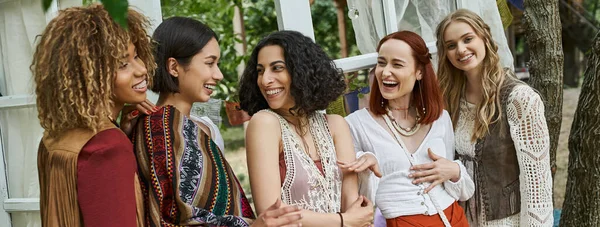 Unbekümmerte multiethnische Freundinnen in Boho-Outfits unterhalten sich in modernem Retreat Center, Banner — Stockfoto