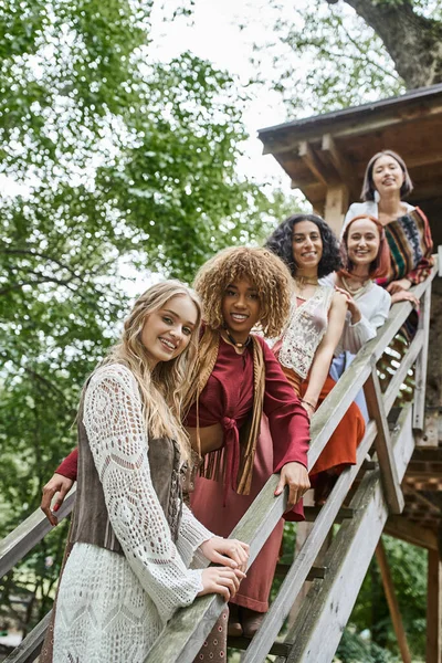 Concepto de retiro de mujeres, mujeres de estilo boho multiétnico sonriendo a la cámara en las escaleras - foto de stock