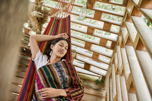Concepto del retiro de las mujeres, mujer joven feliz que relaja en la hamaca en la cabaña, vista superior - foto de stock