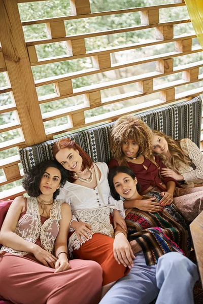 Hochwinkelaufnahme von multirassischen Freundinnen auf der Couch, die in die Kamera schauen und sich im Rückzugszentrum entspannen — Stockfoto
