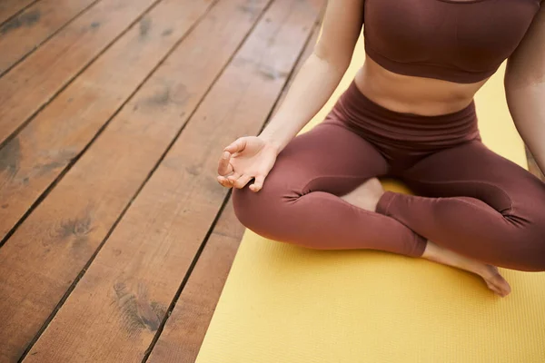 Ausgeschnittene Ansicht einer Frau in Sportkleidung, die Yoga praktiziert, in Lotus-Pose auf Yogamatte — Stockfoto