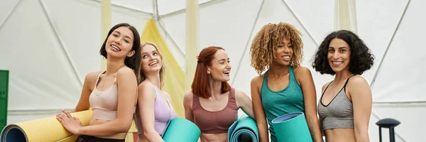 Concept de retraite des femmes, copines multiethniques en vêtements de sport debout avec tapis de yoga, bannière — Photo de stock