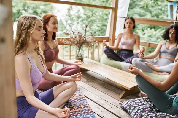 Women retreat, girlfriends meditating in lotus pose in cozy patio of retreat center — Stock Photo