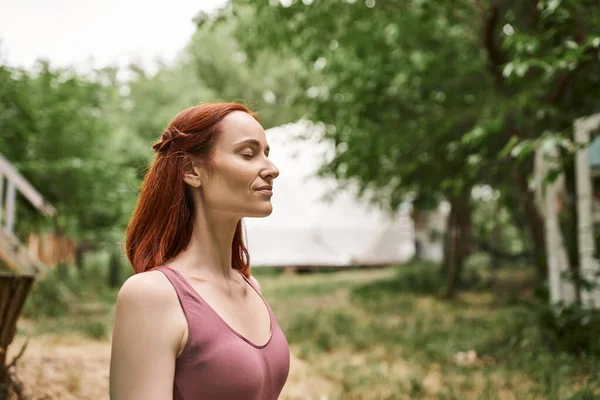 Happy redhead woman meditating with closed eyes in retreat center outdoor — Stock Photo