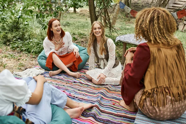 Women retreat, carefree multiethnic boho style girlfriends talking on colorful blanket outdoors — Stock Photo