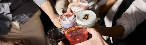 Abgeschnittene Ansicht multiethnischer Kollegen, die in einer Cocktailbar Gläser mit alkoholischen Getränken klappern, Banner — Stockfoto