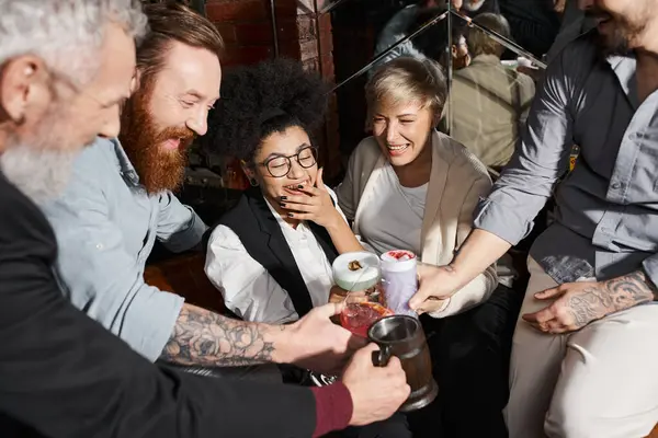 Carefree multiethnic colleagues spending after work time in bar and toasting with alcohol drinks — Stock Photo