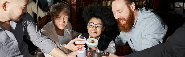 Homem barbudo alegre clinking óculos com colegas multiétnicos passar tempo no bar, bandeira — Fotografia de Stock