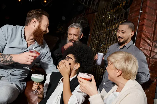 Татуйовані чоловіки і багатоетнічні жінки з коктейлями розмовляють в барі, щасливі колеги за напої — стокове фото