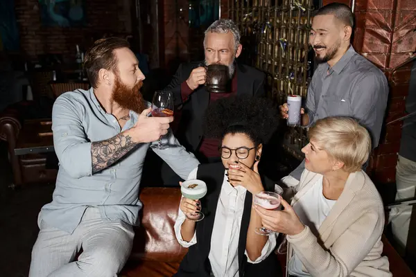 Uomo barbuto tatuato parlando con felici colleghi multietnici con bevande nel bar, dopo il tempo libero di lavoro — Foto stock