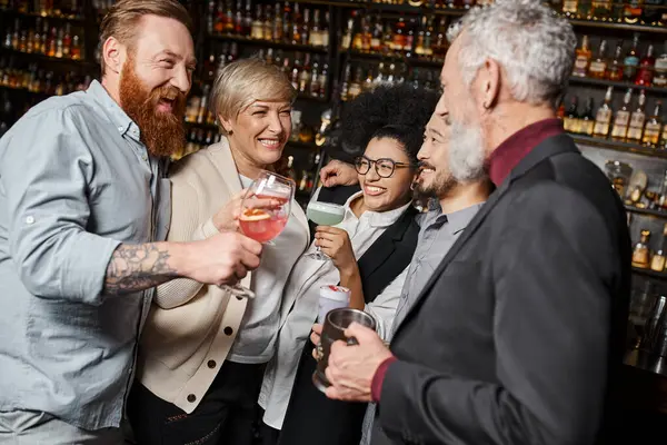 Satisfaits multiethniques compagnons de travail griller avec des cocktails tout en passant du temps dans le bar après le travail — Photo de stock