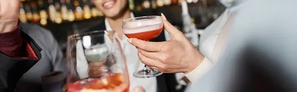 Vue recadrée d'amis de travail multiethniques tenant des verres avec des boissons alcoolisées dans un bar à cocktails, bannière — Photo de stock