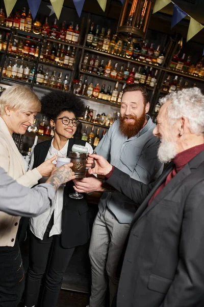 Joyous multicultural colleagues toasting with drinks during after work party in cocktail bar — Stock Photo