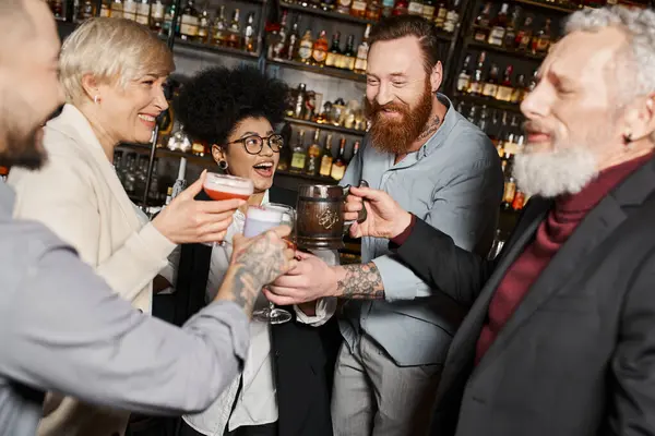Compañeros de trabajo multiétnicos felices pasar tiempo después del trabajo en el bar y brindar con bebidas alcohólicas - foto de stock