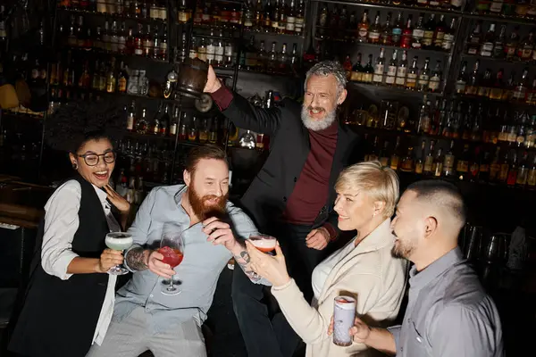 Heureux homme barbu griller avec tasse près d'amis multiculturels tenant des verres à cocktail dans le bar — Photo de stock