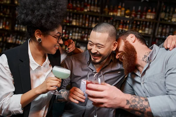 Переполненные радостью многонациональные коллеги по работе с коктейлями, обнимающие и смеющиеся в баре, досуге и веселье — стоковое фото