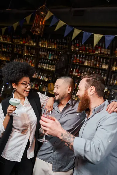 Uomini barbuti multietnici guardando ridere donna africana americana durante dopo la festa di lavoro nel bar — Foto stock