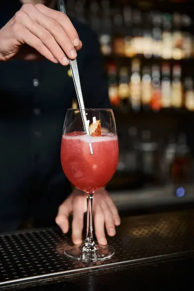 Abgeschnittene Ansicht von Barkeeper Hinzufügen frischer Orangenscheibe in Fruchtalkohol-Cocktail auf der Theke in der Bar — Stockfoto