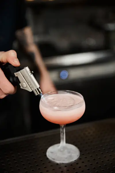 Cropped view of bartender using caramelizer while preparing milk punch in bar, cocktail artistry — Stock Photo