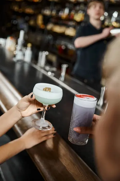 Vista recortada de mujeres multiétnicas que celebran deliciosos cócteles mientras pasan tiempo en el bar después del trabajo - foto de stock