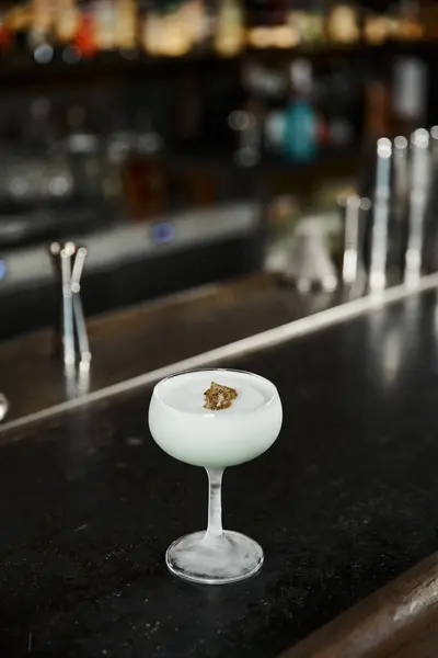 Glass of tasty alcoholic milk punch with kiwi slice on counter in bar, cocktail presentation — Stock Photo