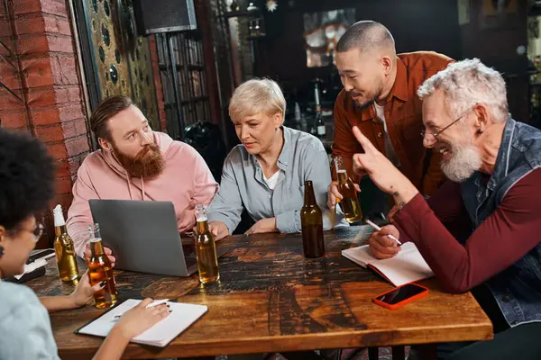 Happy bearded man showing idea sign near creative multiethnic team planning startup in pub — Stock Photo