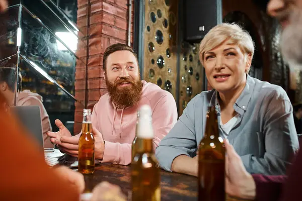 Hombre barbudo emocionado hablando y compartiendo la idea de colegas de negocios sentados en el pub después del trabajo - foto de stock